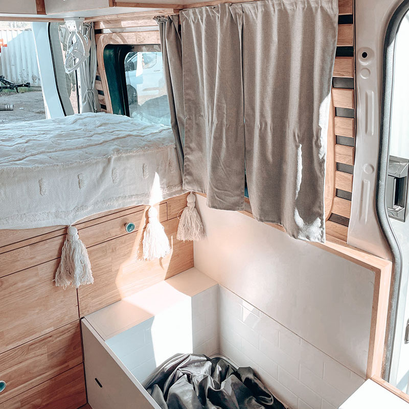 Tiled shower area inside the campervan beside timber cabinetry
